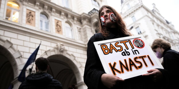 Eine Frau hält ein Schild mit der Aufschrift "Basti ab in Knasti"