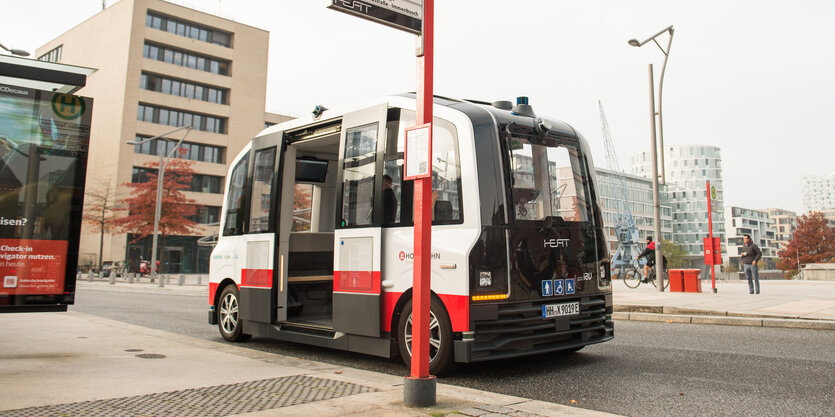 Ein kleiner Bus ohne Fahrer steht mit offener Tür an einer Bushaltestelle