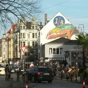 Eine Straßenszene im Bremer Alternativstadtteil "Viertel" im Winter 2018. Historische Gebäude prägen das Bild, an einem weißen Haus zeigt ein großes Graffiti ein buntes Chamäleon und den Schriftzug 1/4