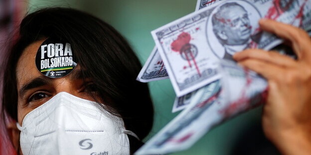 Ein Demonstrant hält eine Nachbildung von US-Dollars in der Hand