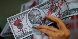 Ein mit roter Farbe beschmierter Geldschein mit dem Portrait von Paulo Guedes