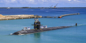 Ein schwarzes, mit Blumen geschmücktes U-Boot liegt in türkisblauem Wasser
