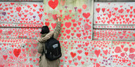 Eine Frau zeichnet ein Herz an die National Covid memorial Wall