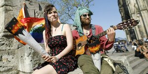 Große Tüten und Gitarrenmusik: ein Mann und eine Frau spielen Hippies