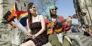 Große Tüten und Gitarrenmusik: ein Mann und eine Frau spielen Hippies