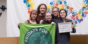 5 junge Menschen mit FFF-Banner und Forderungsschild vor dem Logo der Jugendklimakonferenz