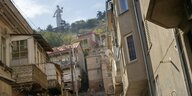 Blick in die Straßen der Altstadt von Tbilissi mit schiefer Kamera, im Hintergrund das Monument der Mutter Georgien