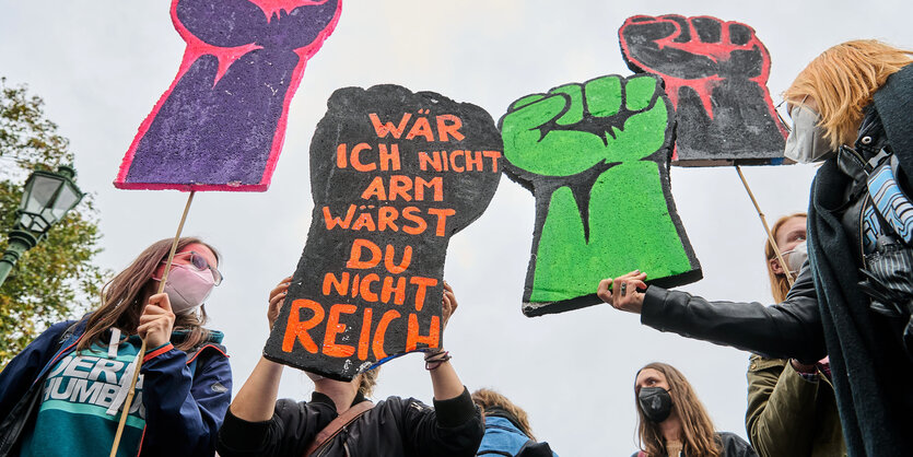 Protestierende halten Schilder hoch, die eine geballte Faust zeigen