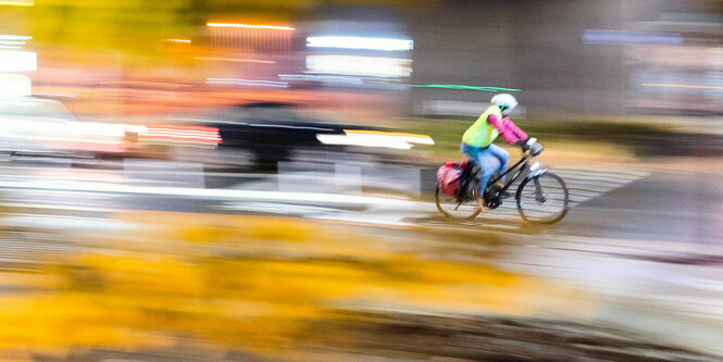 Eine Frau fährt mit einem Fahrrad am frühen Morgen über die Veloroute in die Innenstadt