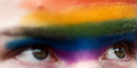 Nahaufnahme zweier Augen in einem mit Regenbogenfarben bemalten Gesicht