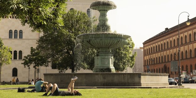 Campus der LMU: Vor einem Brunnen genießen Studenten die SonnesitzenStu