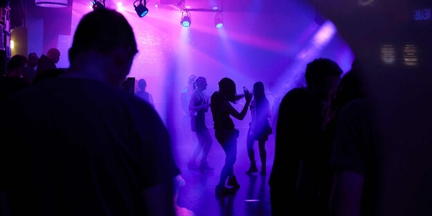 Menschen tanzen in rot-violettes Licht gehüllt