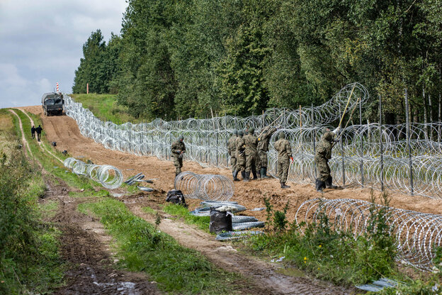 Soldaten errichten einen Stacheldrahtzaun.