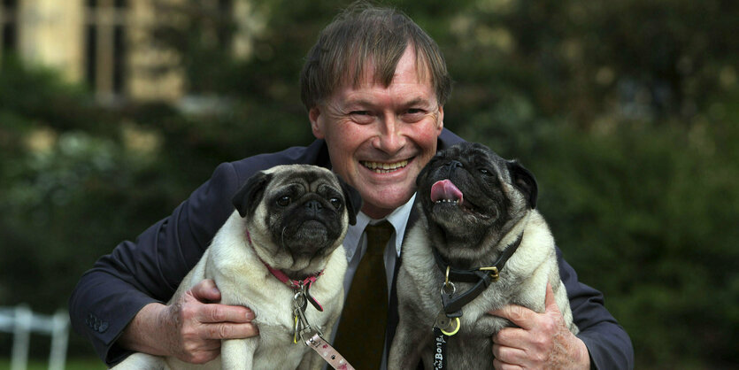 David Amess lässt sich mit seinen zwei Hunden (Möpse) fotografieren