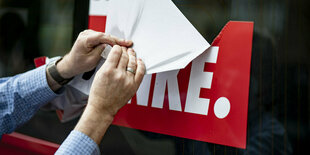 Ein Mitarbeiter reißt einen Aufkleber der Partei Die Linke vor dem Karl-Liebknecht-Haus