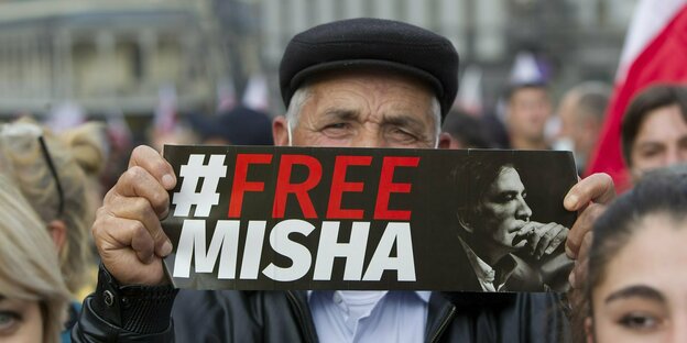 Ein Mann hält ein Plakat mit der Aufschrift «Free Misha»