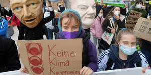 Aktivistinnen halten Schilder in die Höhe, hinter ihnen sind Masken mit den Gesichtern von FDP-Chef Lindner und SPD-Kanzlerkandidat Scholz