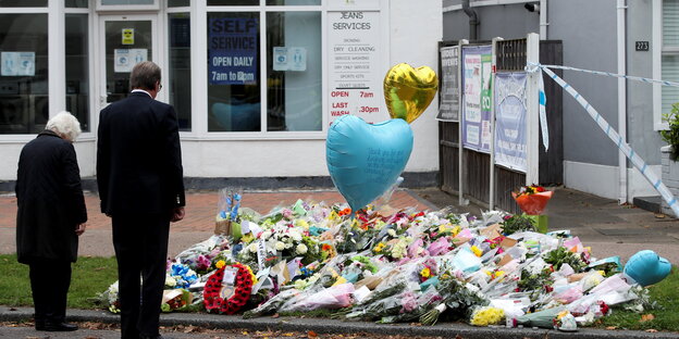 Ein Paar steht vor Blumen auf dem Bürgersteig und einem Ballon in Herzform, wo der Politiker ermordet wurde