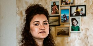 Yalda Farangis Sawgand steht vor einer Wand mit Fotos.