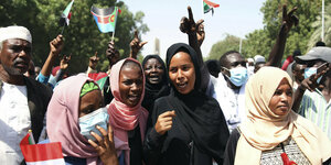 Menschengruppe demonstriert mit sudanesischen Flaggen, im Bild vor allem Frauen
