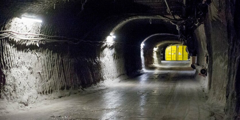 Blick in einen dunklen Stollen, im Hintergrund ist ein gelbes Tor zu sehen