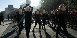 Tanzende Demonstrantenmit großen weißen Masken.