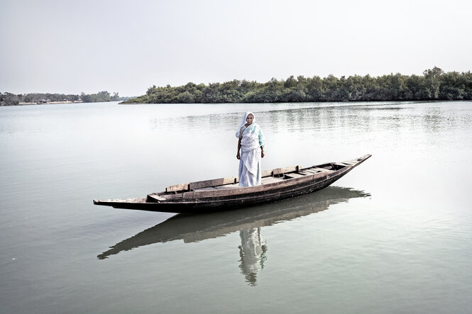 Eine Frau steht in einem Kahn auf dem Wasser