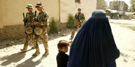 Bundeswehrsoldaten und Zivilisten auf einer straße in Afghanistan.