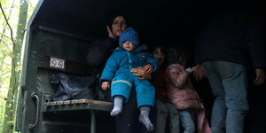 eine Frau mit kleinen Kindern sitzt in einem offenen Lastwagen