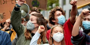 Luisa Neubauer und Greta Thunberg recken die Fäuste bei einer Demonstration.