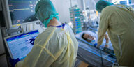Ärzte in Schutzkleidung behandeln auf einer Intensivstation einen Patienten