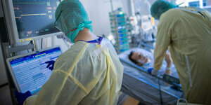 Ärzte in Schutzkleidung behandeln auf einer Intensivstation einen Patienten