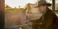 Clint Eastwood im Cowboy-Look mit einem Pferd im Gehege.