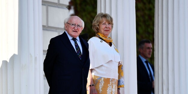 Präsident Michael H. Higgins mit Ehefrau Sabina Coyne vor weißen Säulen.