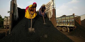 Frauen entladen einen LKW mit Kohle.