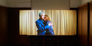 Szene aus der Videoarbeit "∞": Beverly-Glenn Copeland und seine Partnerin sind in Blau gekleidet. Sie umarmen sich.