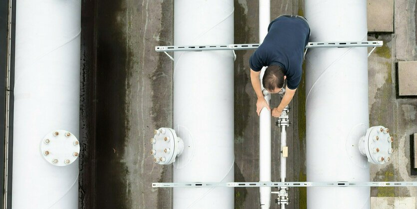 Ein Mitarbeiter beugt sich über weiße dicke Röhren