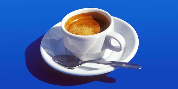 Eine Tasse mit frisch gebrühtem Espresso vor blauen Hintergrund