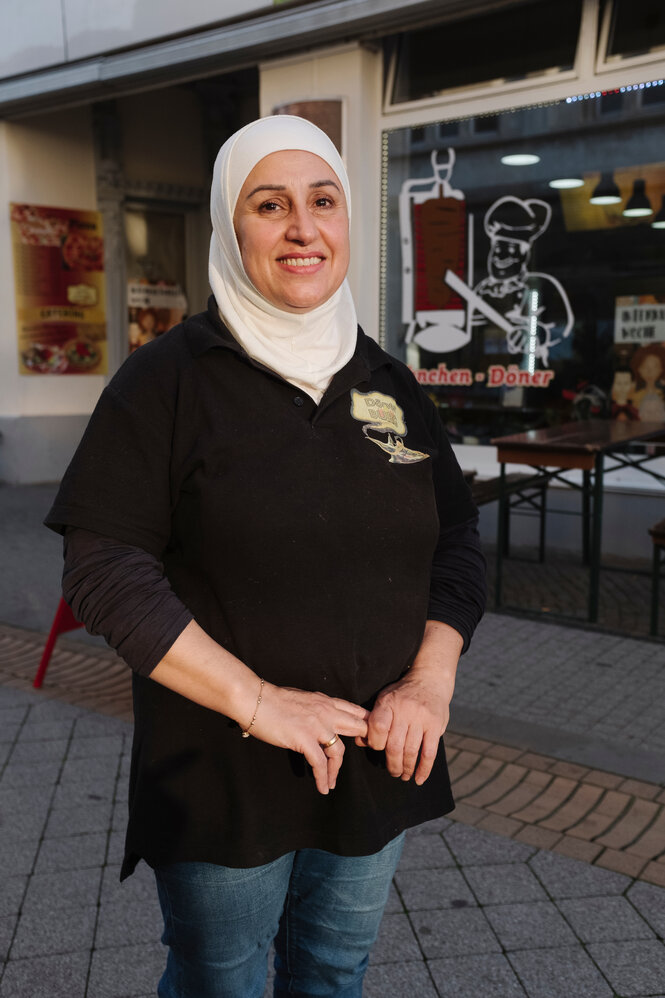 Eine Frau mit Kopftuch vor einem Dönerladen