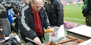 Uli Hoeneß hat in der Münchner Allianz-Arena einen Grill aufbaut und grillt Würstchen.