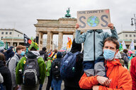 Ein Mann mit einem Kind auf dem Arm steht vor dem Brandenburger Tor