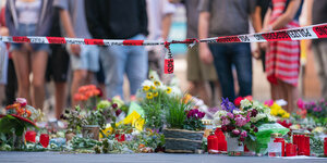 Blumen und Kerzen vor Absperrband der Polizei in Würzburg nach der Tat.