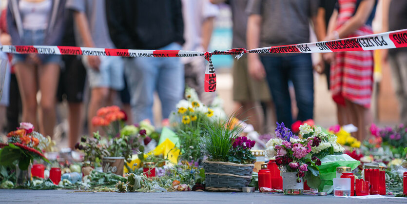 Blumen und Kerzen vor Absperrband der Polizei in Würzburg nach der Tat.