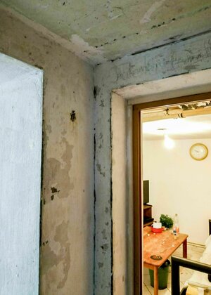 Unverputze Wände, Blick in ein Zimmer in dem ein Tisch steht Unverputze Wände, Blick in ein Zimmer in dem ein Tisch steht