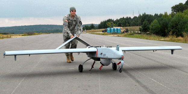 Eine Drone wird von einem Soldaten auf eine Landebahn geschoben