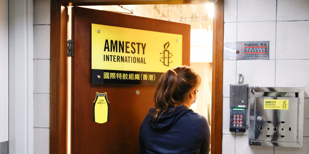 Eine Frau geht durch eine Tür mit dem Aufdruck Amnesty.