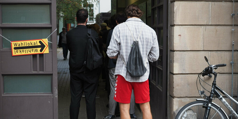 Menschen stehen vor einem Wahllokal Schlange