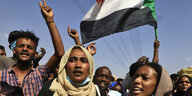 Frauen und Männer protestieren mit der sudanesischen Flagge