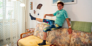 Eine Frau auf einem Sofa strecket ein Bein aus.