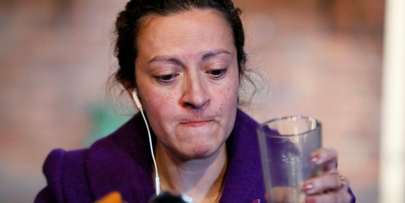 Portrait einer Frau mit einem Glas in der Hand hinter Mikrofonen